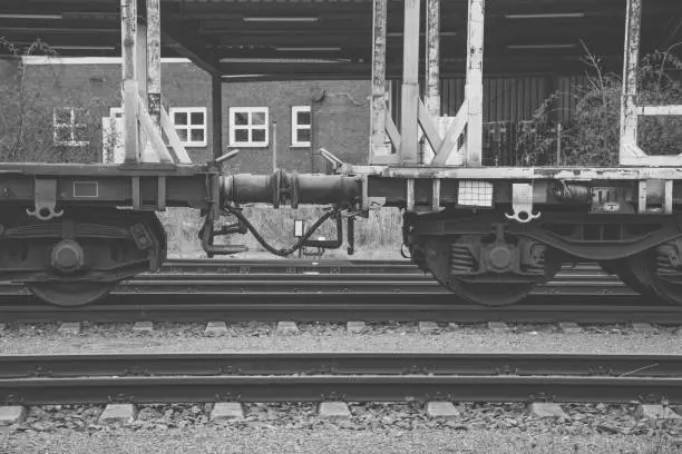 A freight train in a train station in black and white
