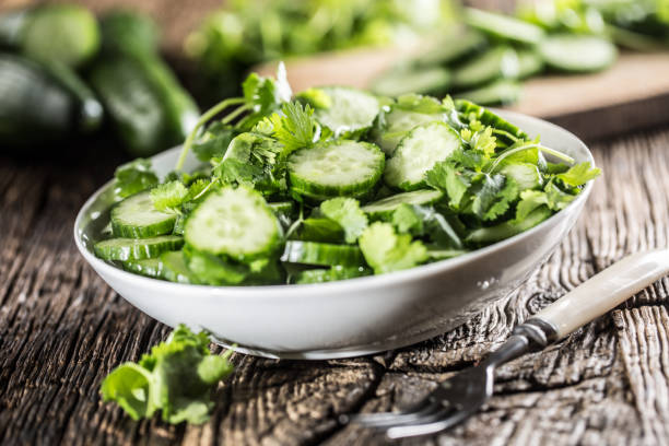 istock Sliced cucumber on a plate with parsley herb on rustic oak wood. 1062713536