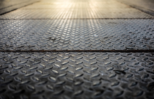Close up of old checker plate steel floor with flare light effect, through the use of moderate, selective soft focus.