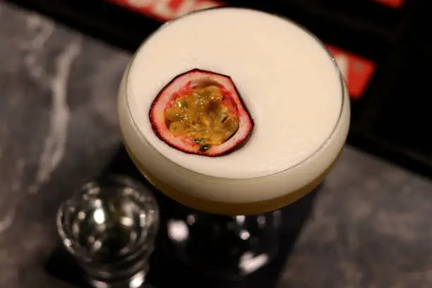A close up of a cut passionfruit sat in a Pornstar Martini cocktail