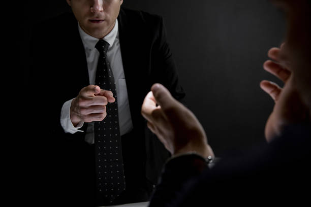 istock Detective pointing hand to criminal man in dark interrogation room 1062744762