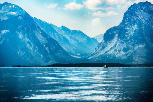 A solitary boat on Jackson lake with the Grand Tetons looming beyond.