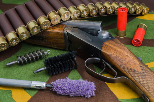 A gloved hand using a wire brush to clean a snubnose revolver isolated on a black mat