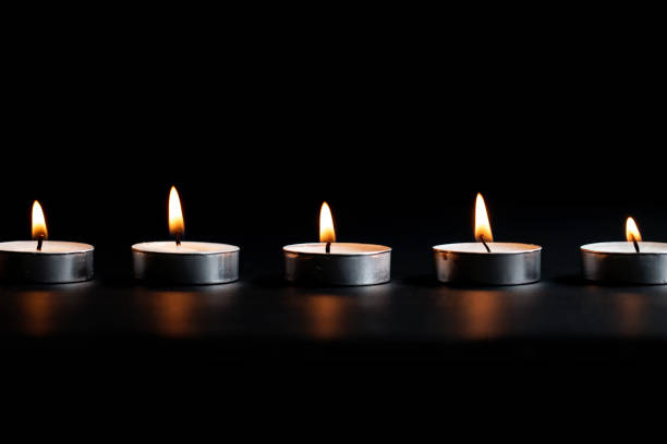 istock Tea Light Candles With Flames Dark Black Background 1062793804