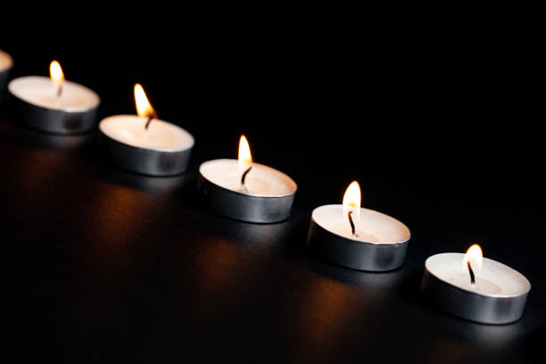istock Tea Light Candles With Flames Dark Black Background 1062793836