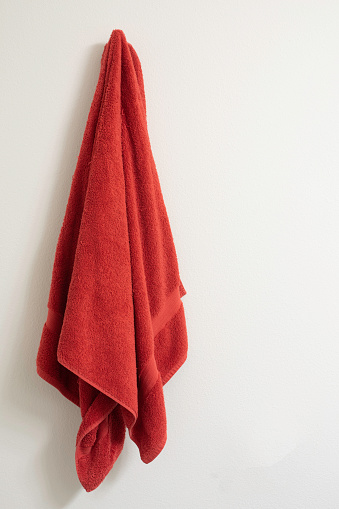 Red towel on a towel hook against a white wall