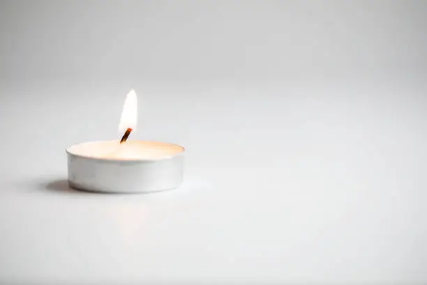 Tea light candles lit with flame on a white background