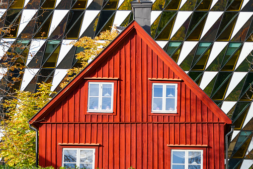 Stockholm, Sweden October 30, 2018 A traditional red stuga or country house is juxtaposed with the shiny Aula Medica modern building at the Karolinska Institute.