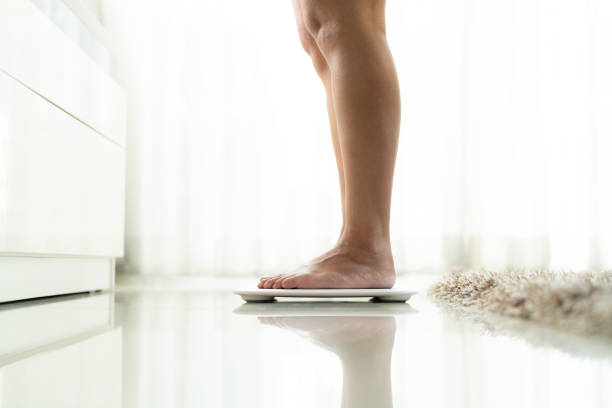 istock young woman standing on digital weight scale 1062819322