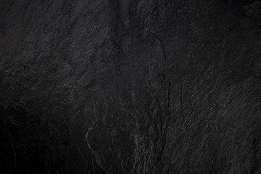 An abstract black slate background, a dark texture with a place for text