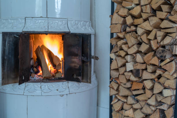 Woman on vacation at mountain cabin. Standing in front of house and enjoying in winter day. Carrying stack of wood for fire.  Wearing warm clothing, hat and scarf. Austrian Alps.