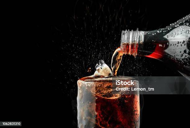 Pour Soft Drink In Glass With Ice Splash On Dark Background Stock Photo - Download Image Now