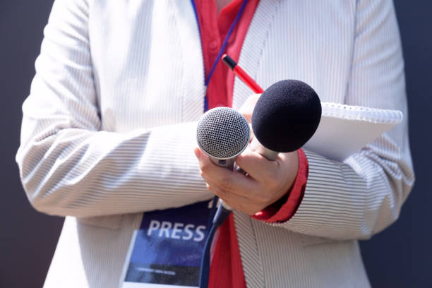 istock Female journalist at news conference, writing notes, holding microphone 1062847734