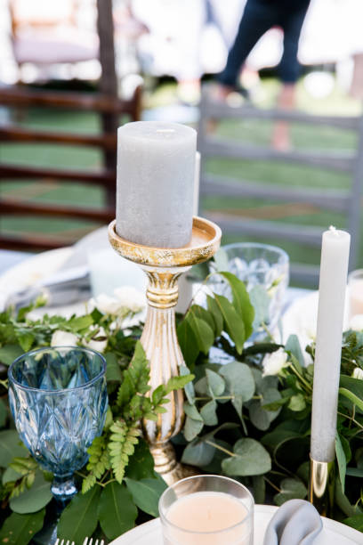 istock Dusty blue candle on hight gold candlestick with green branches on background 1062855732