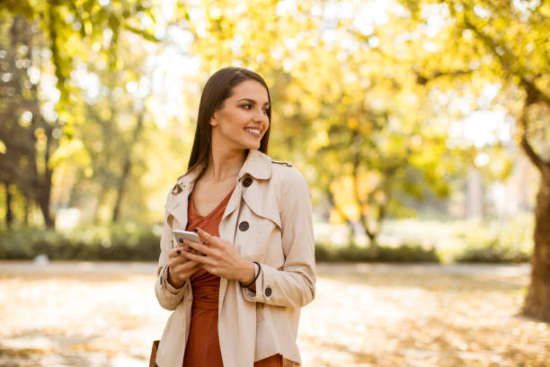 istock Happy young woman using cell phone in autumn park 1062856372