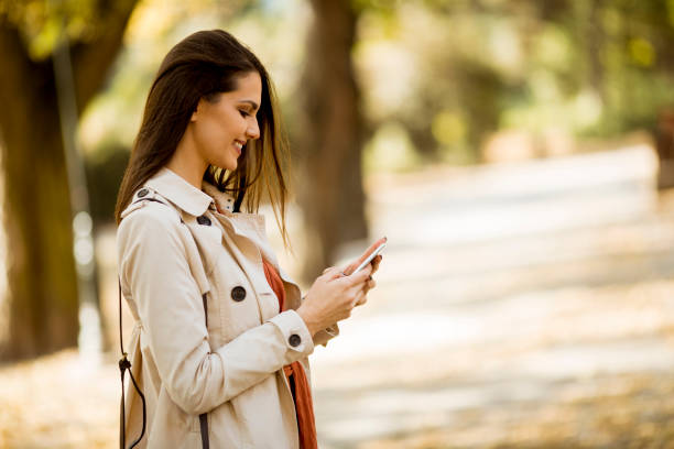 istock Happy young woman using cell phone in autumn park 1062856398