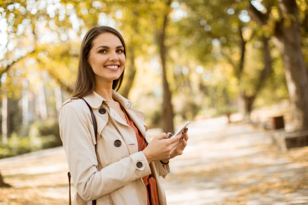 istock Happy young woman using cell phone in autumn park 1062856402