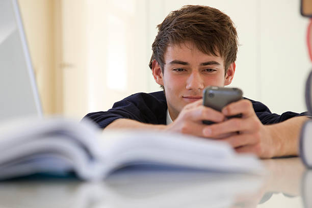 teenage school boy reading a text alert - text messaging mobile phone teenagers only people ストックフォトと画像