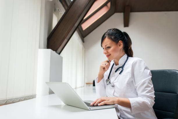 istock Lovely female doctor using laptop. Side view. 1062863260