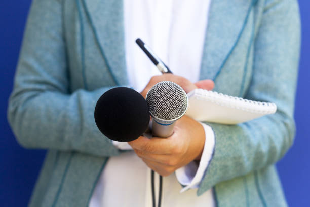 istock Female journalist at news conference, writing notes, holding microphone 1062863926