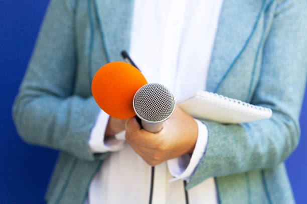 istock Female journalist at press conference, holding microphone, writing notes 1062866824