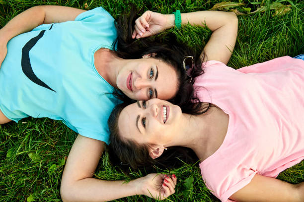 istock Two young happy girls lie on green grass 1062875454