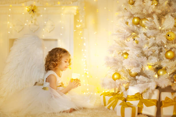 angel child en kerstboom met geschenken geschenken, kid meisje met kaars - engelenpak stockfoto's en -beelden
