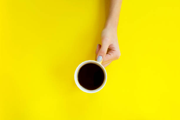 istock Woman hand holding coffee cup on yellow background. 1062879290
