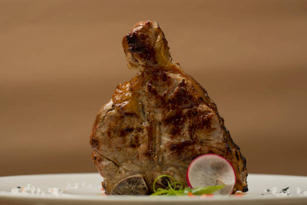 istock Succulent grilled large t-bone steak garnished with herbs, radish and salt, brown background 1062880850