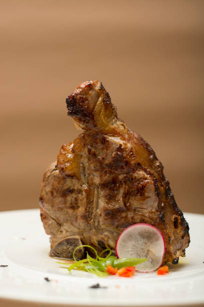 istock Succulent grilled large t-bone steak garnished with herbs, radish and salt, brown background 1062880894