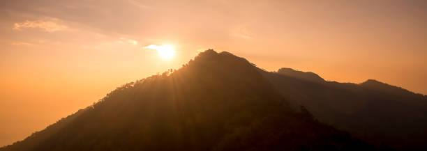 istock Sunset scene on hight mountain. Sunshine through the clouds. silhouette at the mountain. 1062881738