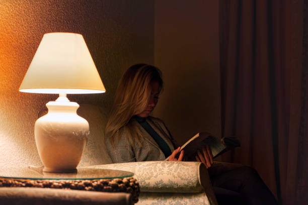 istock Woman reading book in hotel lobby at night with low light 1062889358