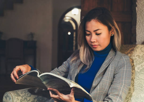 istock Woman reading book in hotel lobby at night with low light 1062891992