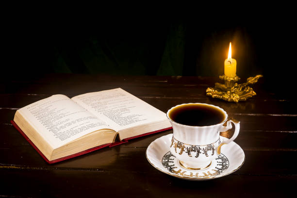 istock Lighted candle in a candlestick with a retro cup, and an open book 1062895306