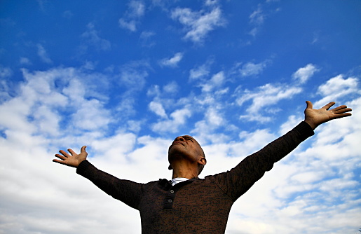 man praying with arms outstretched to the heavens
