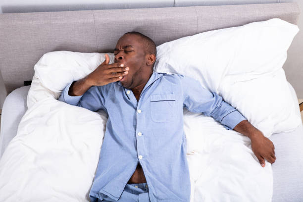 istock Sleepy Man Yawning On Bed 1062905434