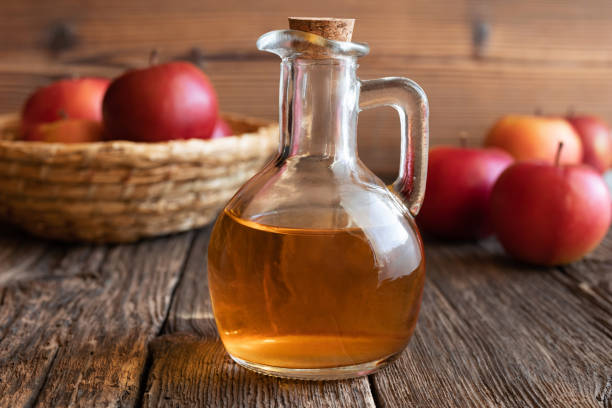A bottle of apple cider vinegar with fresh apples stock photo