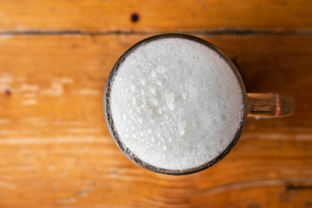 Glass of warm fresh milk with froth on wooden table top