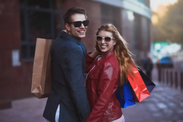 Photo of Beautiful young loving couple carrying shopping bags and enjoying together.