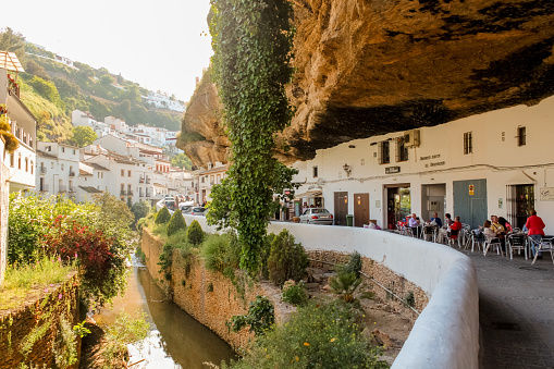 Setenil de las Bodegas, Spain - 5/10/18: Buildings constructed under big rock natural formations in Setenil de las Bodegas. Houses and shops are carved into the rock, providing natural cooling.