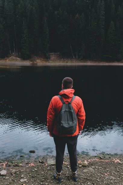 istock Man with backpack wanderlusting at mountain lake 1062935336