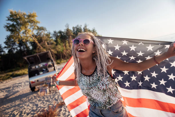 istock Beaming woman with dreadlocks holding America flag while travelling 1062944098
