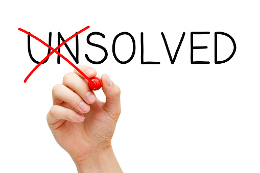 Hand changing the word Unsolved into Solved with red marker isolated on white in solution concept.