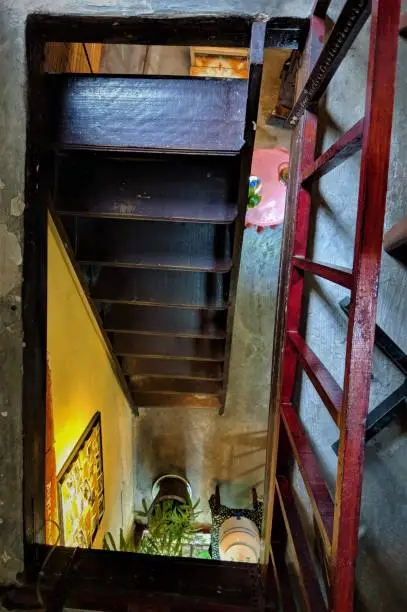 Old staircase in an 100 year old coffee shop. View from top of staircase. The red balcony on the side at a certain angle also looks like a staircase which creates an interestingly confusing combination/picture.
