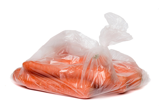 View of some carrots inside a plastic bag isolated on a white background.