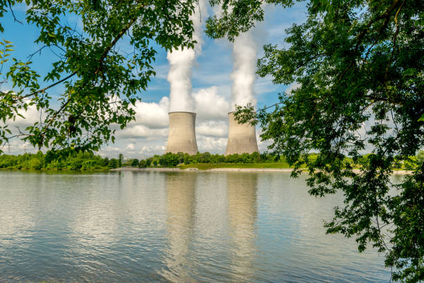 istock Nuclear reactor cooling towers and reflection on a recreation pond framed by trees 1062957908