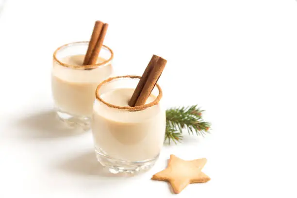 Eggnog with cinnamon and nutmeg for Christmas and winter holidays. Christmas Eggnog, gingerbread cookies isolated on white background.