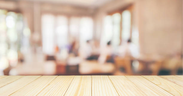 istock Wood table top with Restaurant cafe or coffee shop interior with people abstract defocused blur background 1062974404