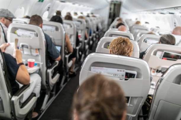 Interior of commercial airplane with passengers in their seats stock photo