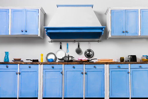 Retro old vintage pin up blue interior kitchen for cooking with kitchen extract and cooking tools: colander, frying pan, toaster, tray and pink sweet cupcakes